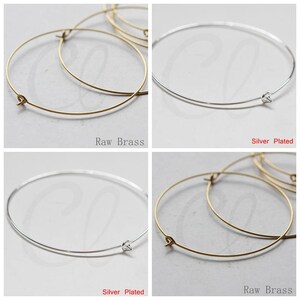 May include: Two hoop earrings, one in raw brass and one in silver plated, shown on a white background. The earrings are simple and elegant, with a delicate wire design.