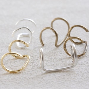 May include: Three pairs of ear cuffs in silver, gold, and brass. Each pair features a double-loop design.