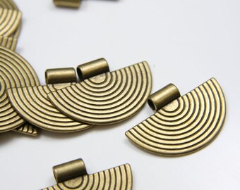 Pode incluir: Um grupo de pingentes de metal de meia-lua de cor dourada com um design de círculos concêntricos. Cada pingente tem um laço na parte superior para prender a uma corrente ou cordão.