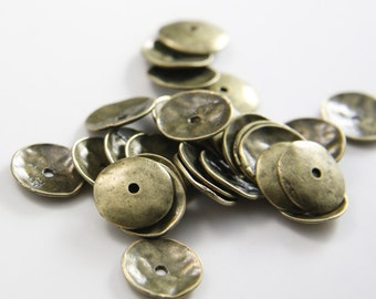 Può includere: Un mucchio di perline in metallo color oro antico con finitura martellata. Le perline sono rotonde con un foro al centro.
