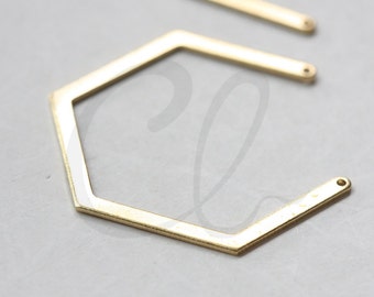 May include: A gold-coloured hexagonal metal frame with rounded corners. The frame is open on all sides and has a smooth, polished finish.  RAW BRASS is printed in red letters at the bottom of the image.