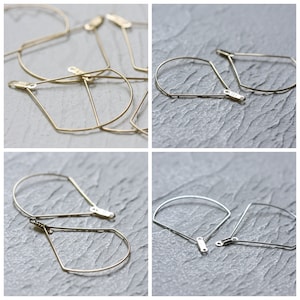 May include: A set of four gold and silver geometric hoop earrings. The earrings are made of thin metal wire and have a simple, modern design.