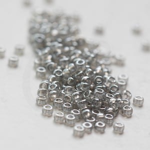 Könnte beinhalten: Ein Haufen kleiner, transparenter Glasperlen mit silbernem Schimmer.