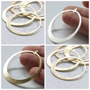 May include: A set of four gold-toned metal hoops with a brushed finish. The hoops are approximately 2 inches in diameter and have a jump ring closure.