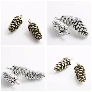 Può includere: Quattro ciondoli a forma di pigna, due argentati e due in bronzo, con un anello per attaccarli a gioielli o artigianato.