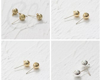 May include: Four pairs of earring findings, two gold, one silver, and one gold and silver. The findings are round and have a post for attaching earrings.