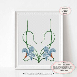 May include: Framed cross-stitch pattern featuring a floral design with blue and orange flowers and green stems. The artwork is presented in a white frame. The image includes the text "Cross Stitch PDF Pattern" and size details in inches and centimeters.