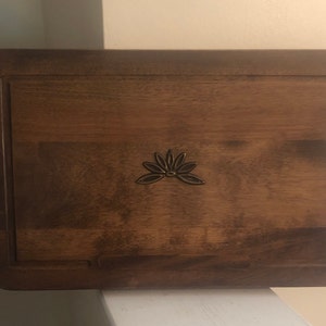 May include: A wooden tray with a raised, decorative, brass floral design in the center. The tray has a dark brown wood finish.
