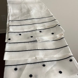 May include: Four white kitchen towels with black polka dots and stripes. The towels are folded and stacked on top of each other.