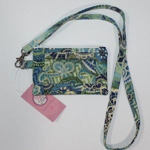 May include: A fabric ID holder with a matching lanyard. The holder and lanyard feature a blue, green, and white paisley pattern. The holder has a clear window and a zipper closure. A pink tag is attached to the holder.