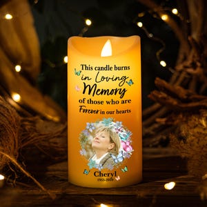 Puede incluir: Una vela amarilla con una foto de una mujer rodeada de mariposas y flores. El texto en la vela dice "Esta vela arde en memoria cariñosa de aquellos que están para siempre en nuestros corazones". El nombre "Cheryl" y las fechas "1955-2020" también están impresas en la vela.