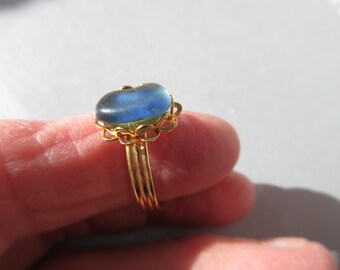 May include: A gold ring with a blue glass oval stone set in a delicate filigree design.