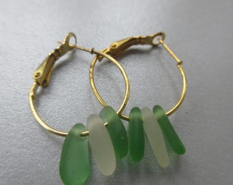 May include: Gold hoop earrings with a dangle of green and white sea glass.