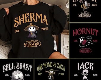 May include: Black sweatshirt featuring the word "SHERMA" in gold lettering, with an illustration of a character and the text "SILKSONG". Additional designs include "SHAKRA", "HORNET", "BELL BEAST", "GARMOND & ZAZA", and "LACE", all with "SILKSONG" text.
