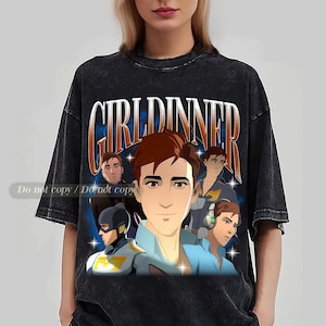 May include: Black graphic t-shirt with a cartoon illustration of a man with brown hair and the text "GIRL DINNER" in a retro style. The design includes multiple images of the same character in different poses, set against a blue starry background.