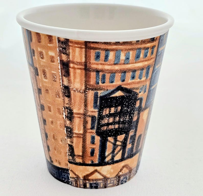 Puede incluir: Un vaso de caf&eacute; de papel con borde blanco, decorado con una ilustraci&oacute;n detallada de una fachada de edificio. El dise&ntilde;o presenta tonos marrones, azules y negros, con elementos arquitect&oacute;nicos, dando un aire vintage.