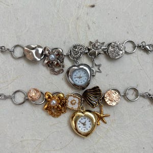 Peut inclure: Deux bracelets à breloques argentés et dorés avec des montres en forme de cœur, les breloques comprennent des fleurs, des étoiles, des coquillages et un soleil.