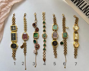 Può includere: Sette orologi vintage color oro con varie forme e colori del quadrante, tra cui quadrati, rettangolari e ovali. Ogni orologio ha un design unico ed è collegato da una catena. Alcuni hanno ciondoli decorativi.
