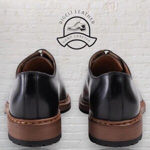 May include: A pair of black leather oxford shoes with brown soles. The shoes are hand-crafted and feature the text "Rigelli Leather Hand Crafted".