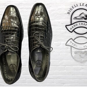 May include: A pair of black leather dress shoes with crocodile embossed pattern. The shoes have lace-up closures and are hand-crafted.