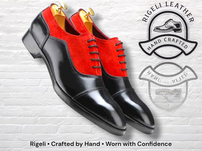 May include: Pair of black leather dress shoes with red suede panels. The shoes have a glossy finish and are laced up with black laces. The image includes the text "Rigeli &bull; Crafted by Hand &bull; Worn with Confidence."