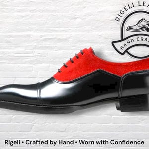 May include: A black and red leather dress shoe with a cap toe and a low heel. The shoe has a red suede upper and black leather on the toe and sides. The shoe is hand crafted. The text "Rigeli Leather" and "Hand Crafted" are in the image.