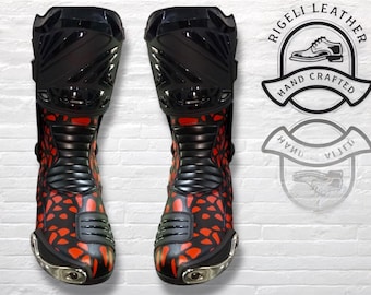 Könnte beinhalten: Paar schwarze und rote Motorradstiefel mit einem einzigartigen Muster. Die Stiefel haben ein glänzendes Finish und metallische Akzente. Das Bild enthält auch ein Logo mit der Aufschrift "Rigeli Leather Hand Crafted".