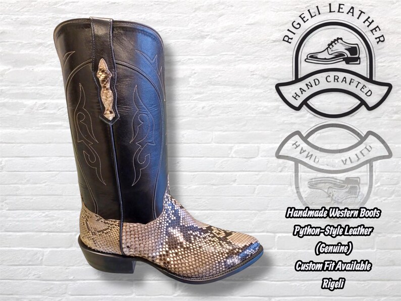 Pu&ograve; includere: Stivale western fatto a mano in pelle nera e marrone stile pitone. Lo stivale ha una tomaia nera con cuciture decorative e un motivo a pelle di serpente nella parte inferiore. Il testo "Rigeli Leather" e "Hand Crafted" &egrave; visibile.