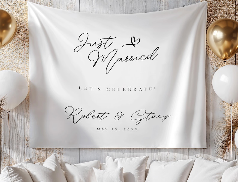 May include: White fabric backdrop with the words "Just Married" in elegant black script, along with "Let's Celebrate!" and the names "Robert & Stacy" with a date. Gold and white balloons are visible.