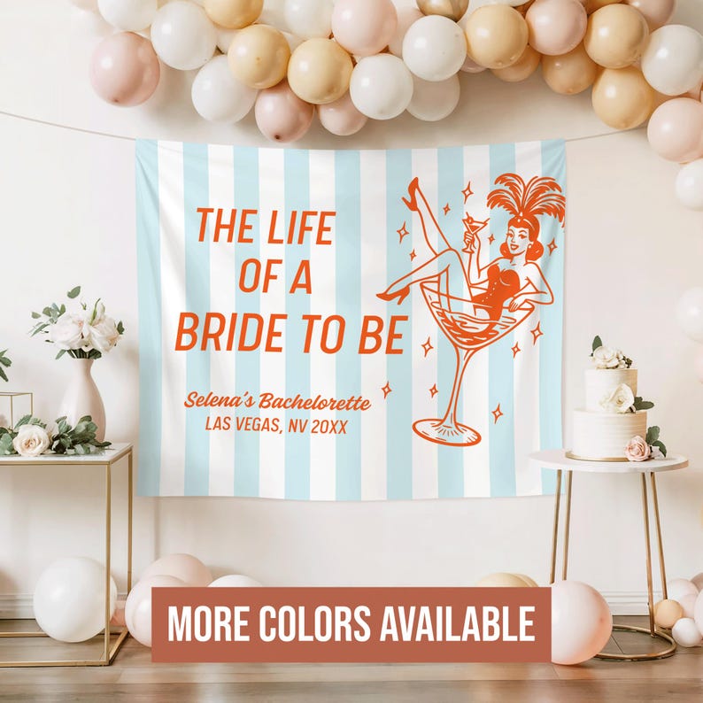 May include: A light blue and white striped backdrop with the text "THE LIFE OF A BRIDE TO BE" in orange. The backdrop features a retro illustration of a woman in a martini glass. The text "Selena's Bachelorette, Las Vegas, NV 20XX" is also visible.