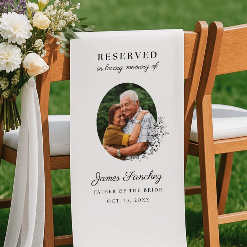 May include: A white fabric memorial sign draped over a wooden chair, featuring the text RESERVED in loving memory of, a circular photo of two people embracing, and the name James Sanchez, FATHER OF THE BRIDE, OCT. 13, 20XX with floral accents.