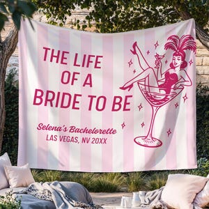 May include: A pink and white striped banner with the text "THE LIFE OF A BRIDE TO BE" in pink. The banner features a graphic of a woman in a martini glass. The banner also includes the text "Selena's Bachelorette LAS VEGAS, NV 20XX".