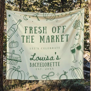 Może przedstawiać: Kremowy baner z zielonymi ilustracjami i tekstem. Na banerze widnieje napis "FRESH OFF THE MARKET" nad "LET'S CELEBRATE Louisa's BACHELORETTE EST. 20XX". Baner jest ozdobiony dyniami, kieliszkami do wina i innymi świątecznymi grafikami.