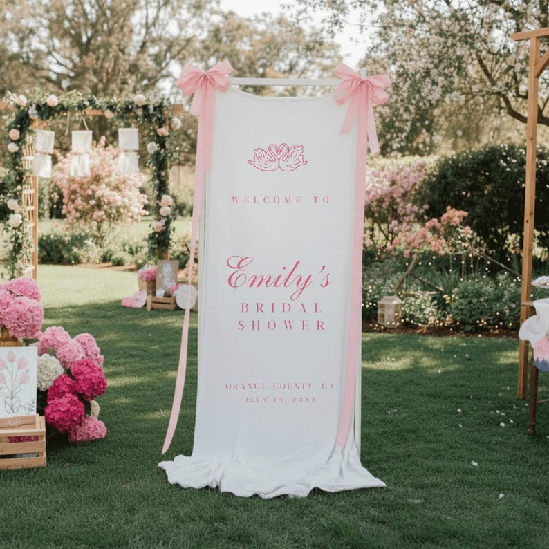 Puede incluir: Una pancarta blanca con texto y detalles en rosa, que anuncia "Bienvenida a la despedida de soltera de Emily". La pancarta est&aacute; adornada con lazos y cintas rosas, y presenta un dise&ntilde;o de cisne. Los detalles del evento incluyen la ubicaci&oacute;n y la fecha.