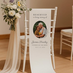 May include: A white wedding chair sign featuring a vertical banner with the text RESERVED in loving memory of, a circular photograph of two people, and the name James Sanchez, FATHER OF THE BRIDE, OCT. 13, 20XX, accented by a floral bouquet.