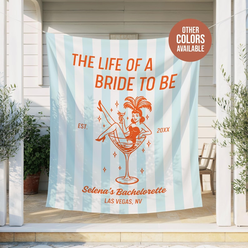 May include: A light blue and white striped banner with the text "THE LIFE OF A BRIDE TO BE" in orange. An illustration of a woman in a martini glass is featured. The banner also includes "Selena's Bachelorette, Las Vegas, NV."