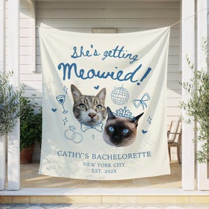 Könnte beinhalten: Ein cremefarbenes Banner mit dem Text "She's getting Meowied!" in blauer Schrift. Zwei Katzenköpfe sind abgebildet, zusammen mit Illustrationen einer Discokugel, einer Schleife und Ringen. Auf dem Banner steht "Cathy's Bachelorette, New York City, Est. 202X."