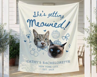 Può includere: Un banner color crema con la scritta "She's getting Meowied!" in blu. Sono raffigurati due volti di gatto, insieme a illustrazioni di una palla da discoteca, un fiocco e anelli. Il banner recita "Cathy's Bachelorette, New York City, Est. 202X."