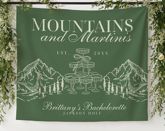 Puede incluir: Telón de fondo verde con el texto "MOUNTAINS and Martinis" y "Brittany's Bachelorette JACKSON HOLE". El diseño incluye ilustraciones de montañas, árboles y una torre de champán. El telón de fondo está decorado con detalles florales.