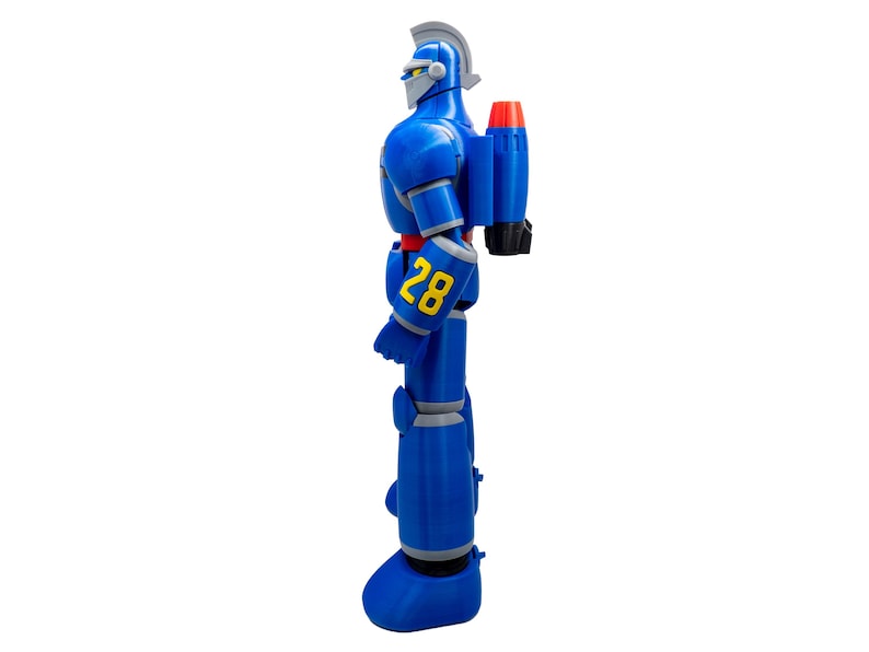 May include: A blue robot action figure with a silver helmet and accents. The robot has a red and black rocket pack and the number "28" in yellow on its arm. The figure is standing on a white background.