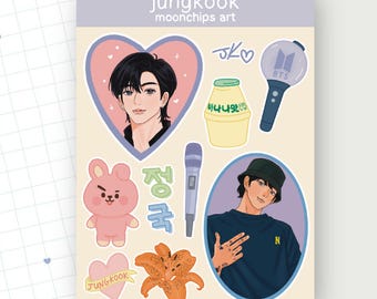 Puede incluir: Una hoja de pegatinas con ilustraciones de una persona, un conejito rosa, un micrófono, una bebida con sabor a plátano, un bastón luminoso y una flor. La hoja tiene el texto "Jungkook" y "moonchips art".