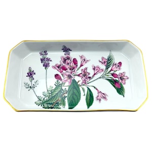 May include: A rectangular white ceramic tray with a gold rim. The tray is decorated with a floral design featuring pink and purple flowers, green leaves, and stems. The tray is a decorative item.