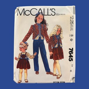 May include: A McCall's 7645 sewing pattern envelope featuring illustrations of three children wearing matching floral print jackets with blue trim, paired with either a dark brown jumper dress or dark blue pants. The text includes the number 7645.