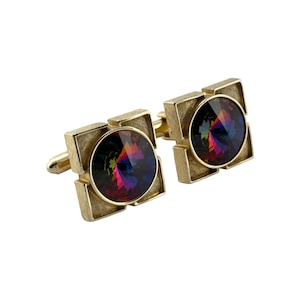 May include: A pair of gold-toned cufflinks with a square design. Each cufflink features a large, round, iridescent crystal in shades of purple, blue, and green. The cufflinks have a classic, elegant style.