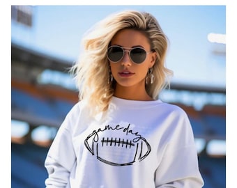 May include: White sweatshirt with a black graphic of a football and the text "game day".
