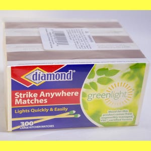 Pode incluir: Uma caixa de fósforos Diamond Strike Anywhere. A caixa é branca com um logotipo vermelho, azul e amarelo. O texto "Strike Anywhere Matches" e "Lights Quickly & Easily" é visível. A caixa contém 300 fósforos grandes de cozinha.