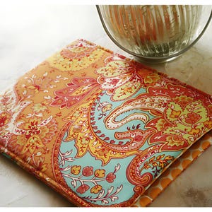 May include: A colorful paisley patterned fabric cover with orange, red, yellow, blue, and white colors. The cover is made of a soft, quilted fabric.