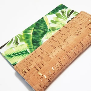 May include: A brown cork wallet with a green and white tropical leaf print on the inside. The cork has a gold fleck finish.
