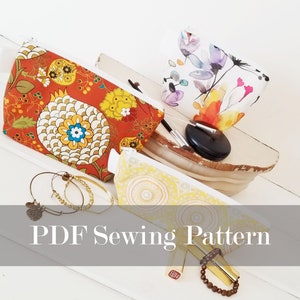 May include: A PDF sewing pattern for making a zippered pouch. The image shows three pouches with different fabric designs: a floral pattern, a yellow pattern with circles, and a red pattern with flowers. The text "PDF Sewing Pattern" is displayed on a gray background.