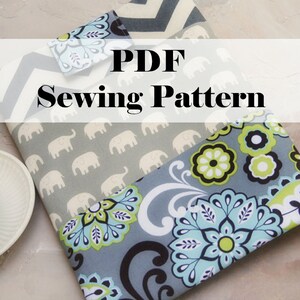 May include: PDF Sewing Pattern for a gray and blue fabric pouch with a floral design and elephant print. The pouch is folded and lying on a light gray surface.